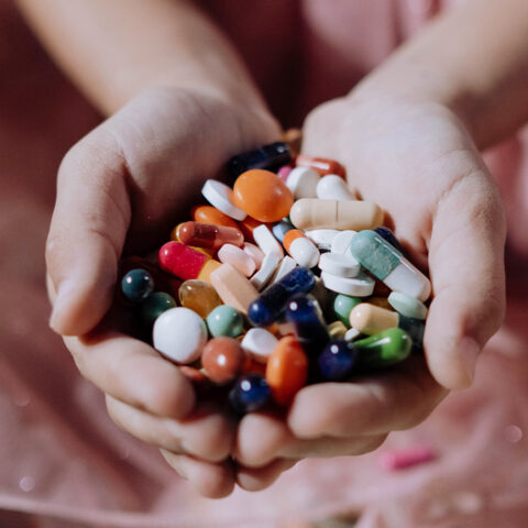 Close up of hands full of a variety of colorful pills