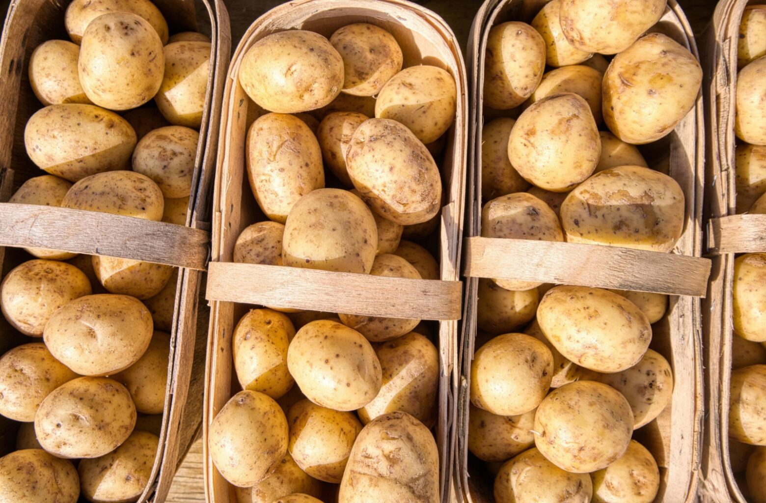 From above, potatoes in four wooden baskets.