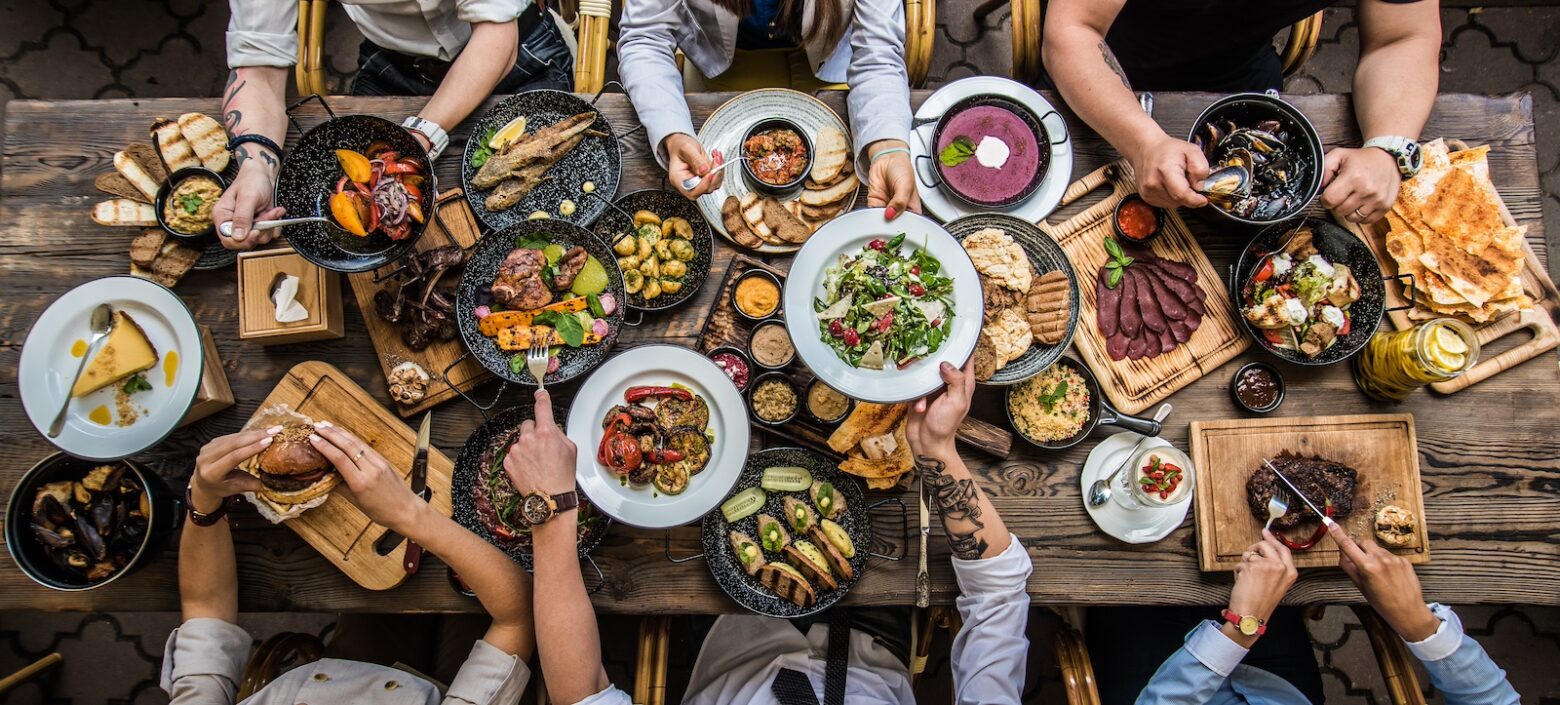 Above shot of friends and family having dinner at a long wooden table.