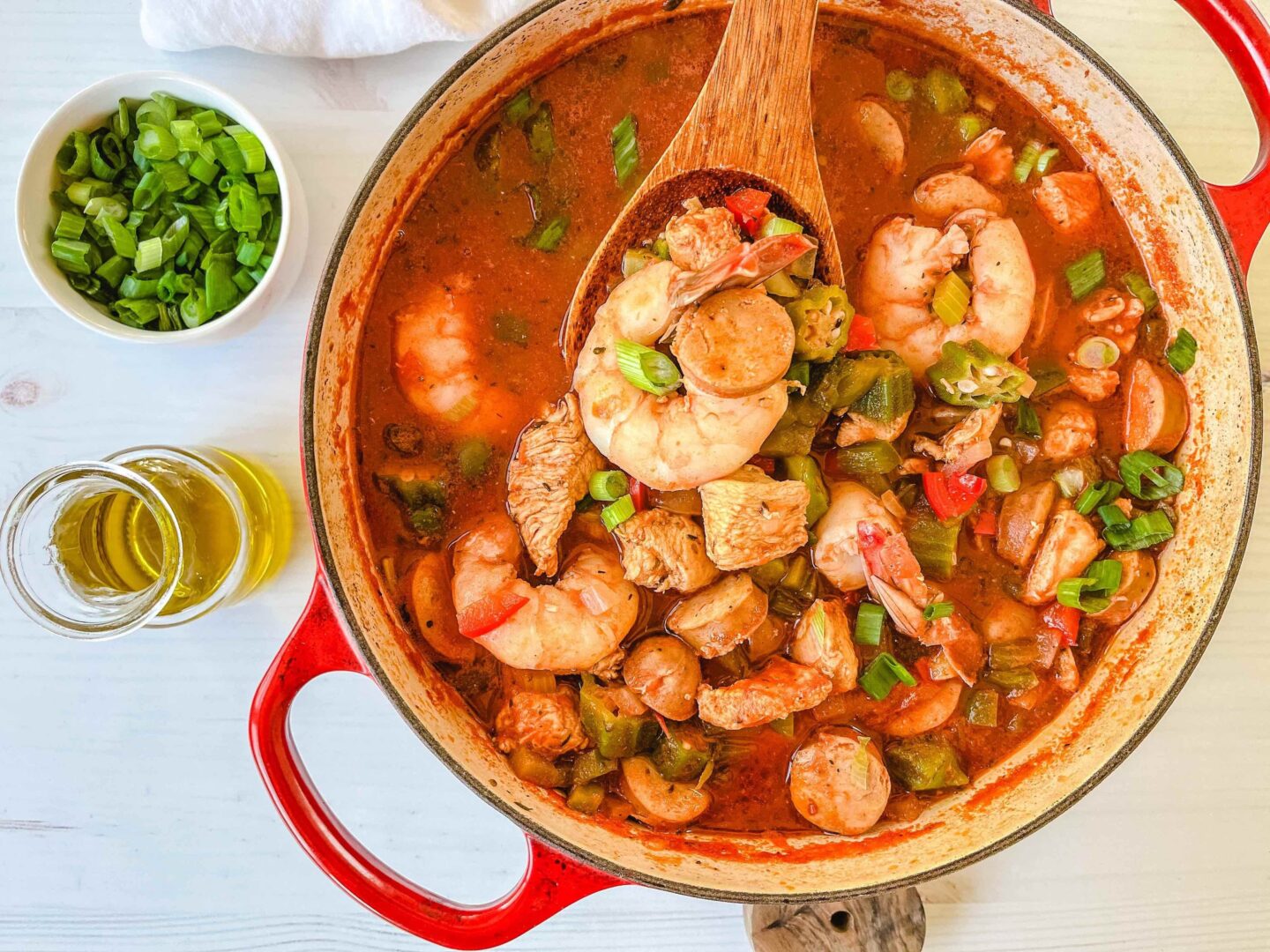 Paleo Jambalaya in a dutch oven cooking with a wooden spoon. 