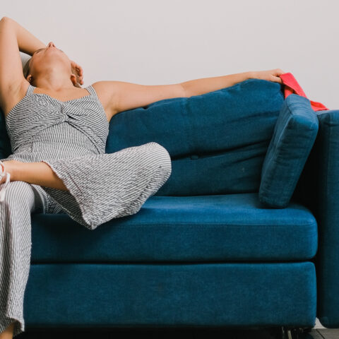 Exhausted woman lying back on a couch