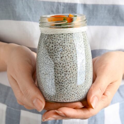 Close up of a woman holding a jar of chia pudding.