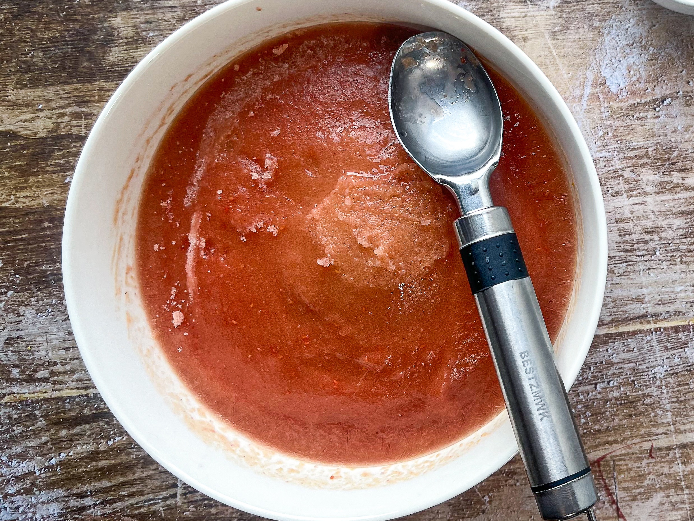 Frozen peach sherbet in a bowl with an ice cream scoop