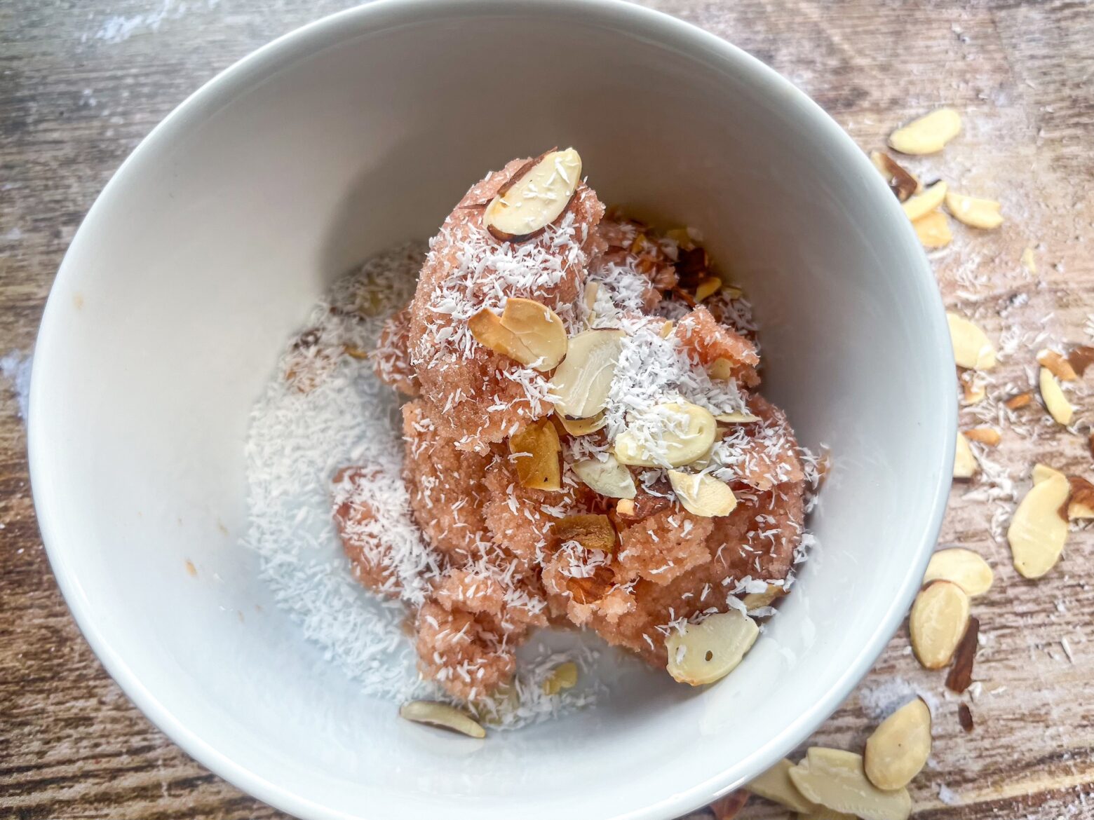 Finished peach sherbet in a bowl with almonds and shredded coconut