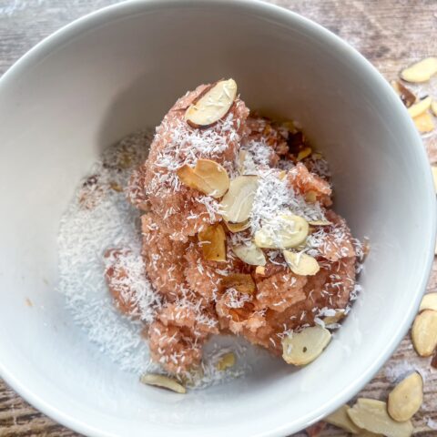 Finished peach sherbet in a bowl with almonds and shredded coconut