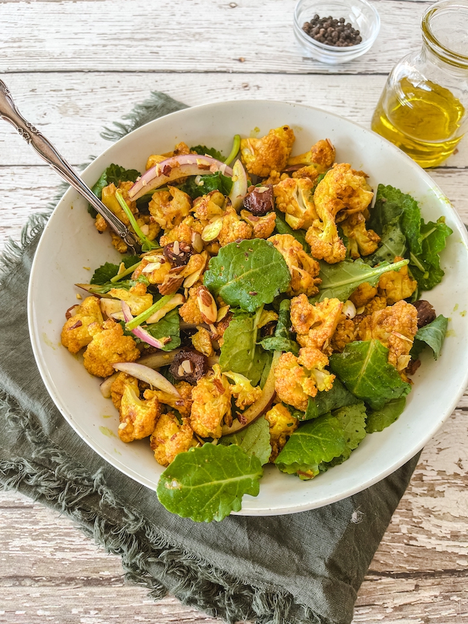 roasted cauliflower and arugula salad plated with fork