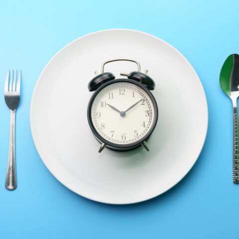 Analog alarm clock on an empty plate with tableware setting