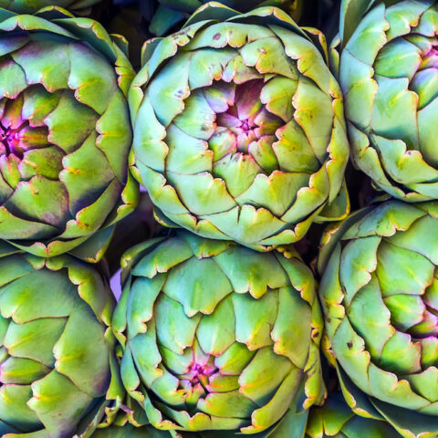 Six artichokes side-by-side from above.