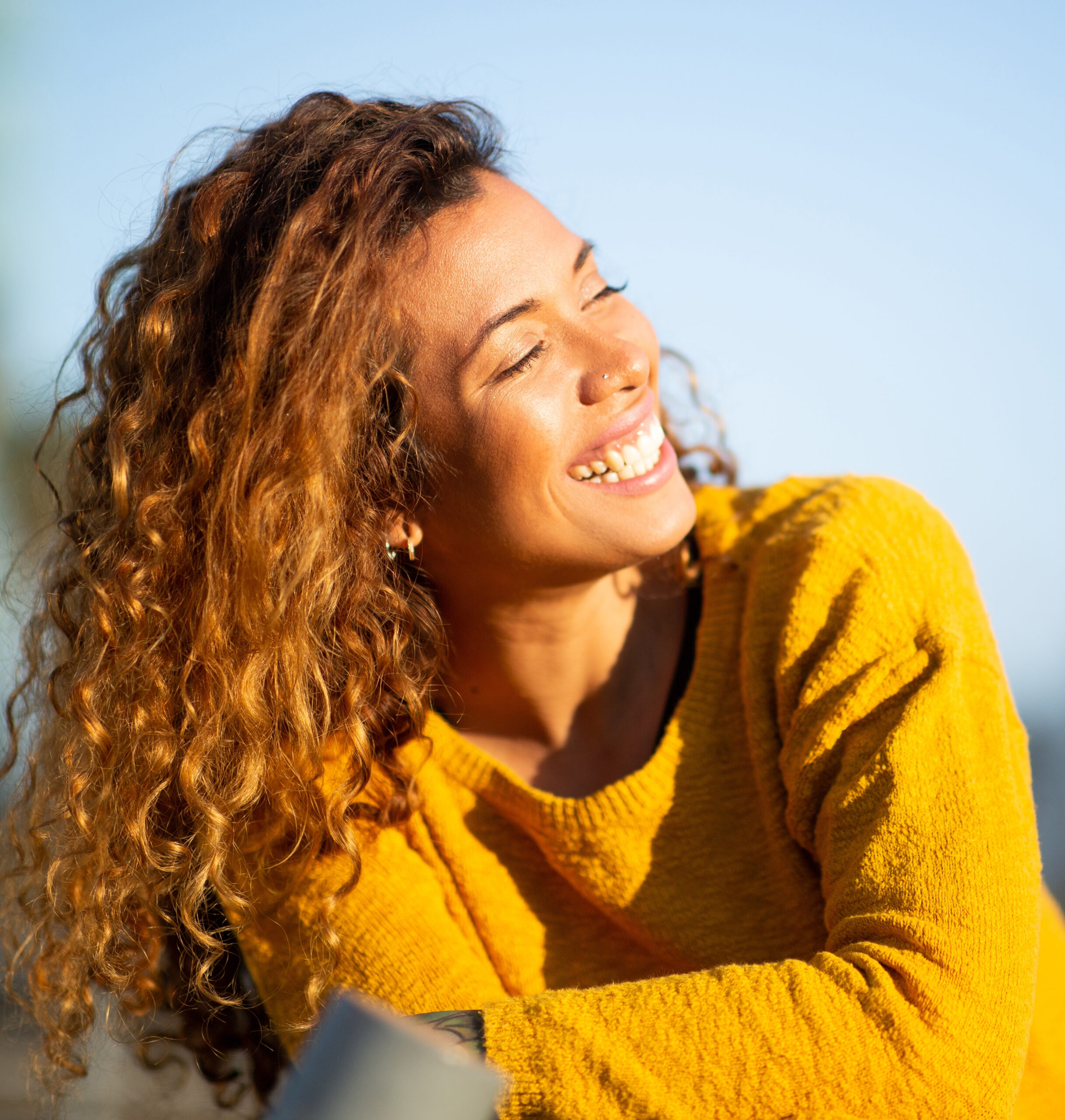 A smiling young woman in a gold sweater.