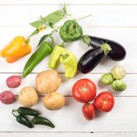 A variety of nightshade vegetables laid out on a table.